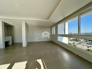 Ambiente interno de uma sala ampla com grandes janelas que oferecem uma vista da paisagem.