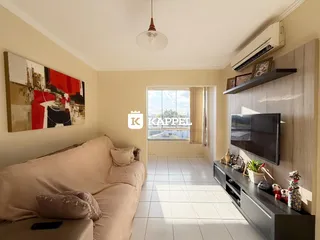 Sala de estar com sofá e televisão em um ambiente claro.
