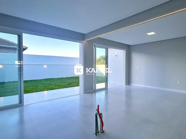 Sala de estar com grandes portas de vidro que oferecem vista para um gramado verde.