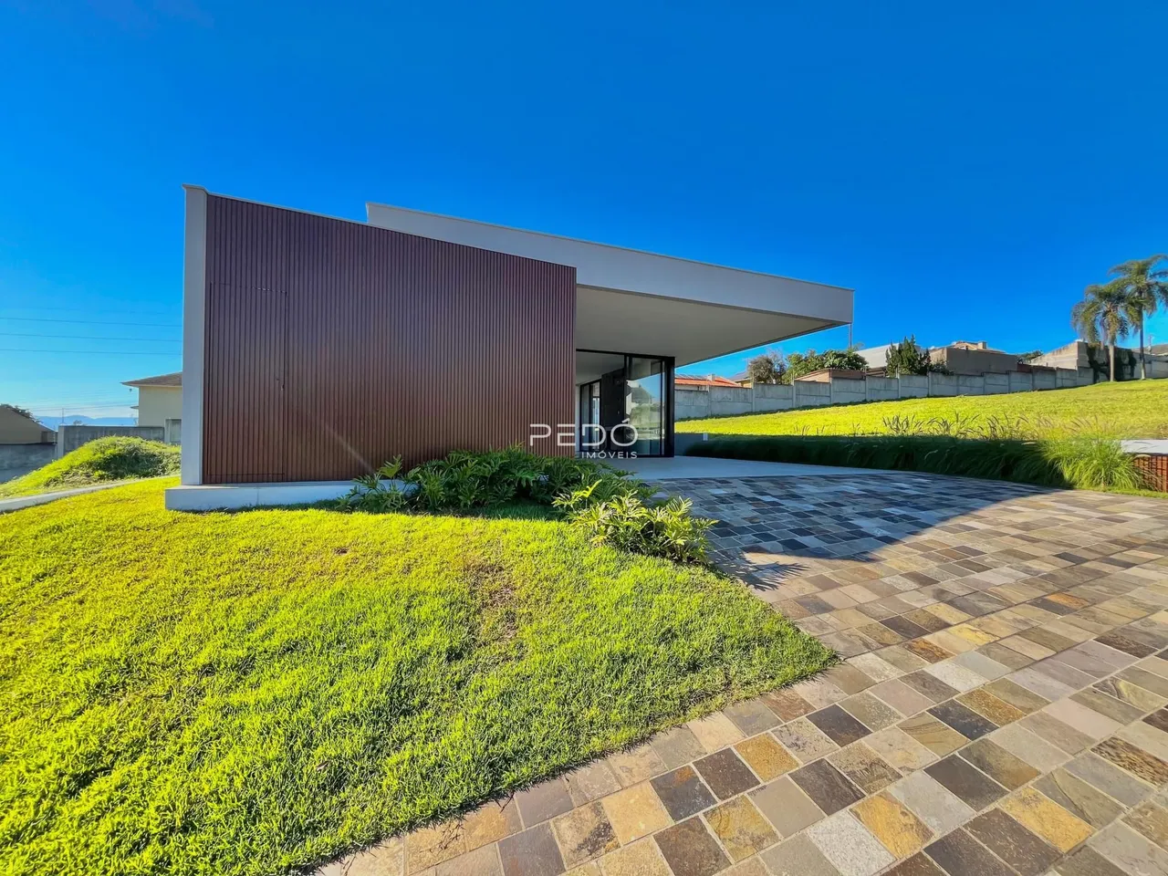 Fachada de uma casa moderna em Lajeado, Brasil, com jardim e área pavimentada.