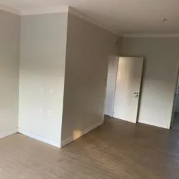 Hall de entrada com paredes brancas e piso de madeira.