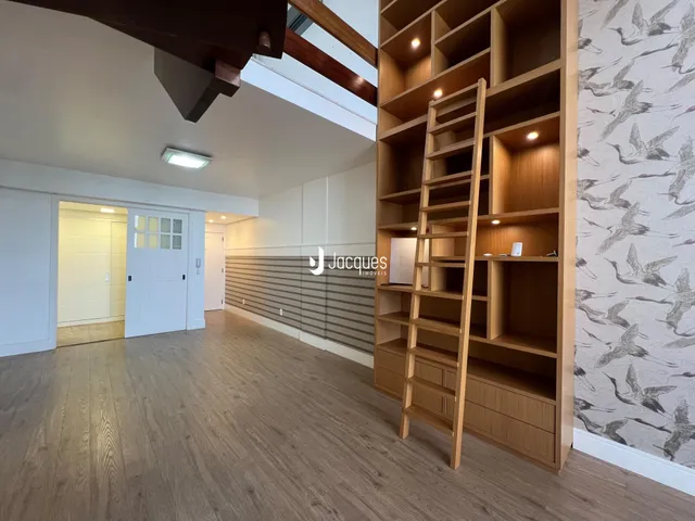 Interior de uma sala com piso de madeira e estante de madeira.