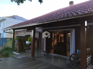Fachada de uma residência com deck de madeira e área coberta.