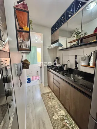 Vista interna de uma cozinha com armários de madeira e bancada escura.