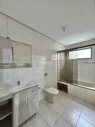 Banheiro com revestimento de azulejos brancos e bancada de pia.
