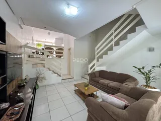 Sala de estar com sofá e escadaria em um imóvel no Brasil.