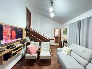 Sala de estar com escadaria de madeira e sofá claro.
