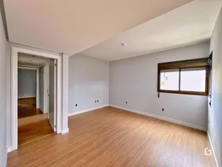 Vista interna de uma sala com piso de madeira clara e paredes cinzas.