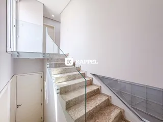 Escadaria moderna com guarda-corpo de vidro em um interior claro.