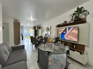 Sala de estar e jantar com sofá e televisão montada na parede.