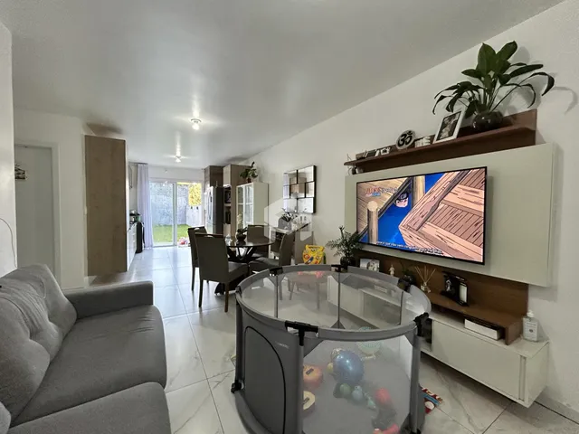 Sala de estar e jantar com sofá e televisão montada na parede.