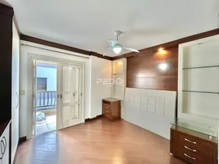 Ambiente interno com piso de madeira e porta de vidro abrindo para uma varanda.
