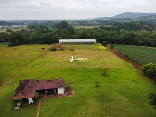 Vista aérea de uma propriedade rural com campo gramado e edificações rústicas.