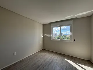 Ambiente interno de uma sala com piso de madeira clara e grande janela.