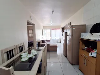 Foto de um corredor de apartamento mostrando uma mesa de jantar e a área da cozinha.