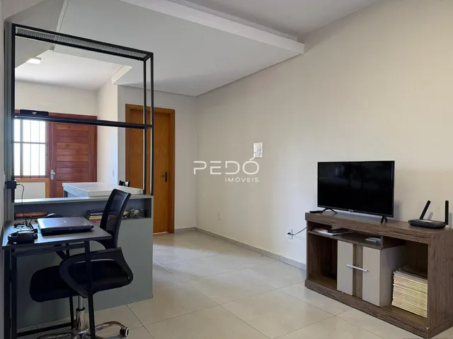 Sala de estar com paredes brancas e móveis de madeira no interior do imóvel.