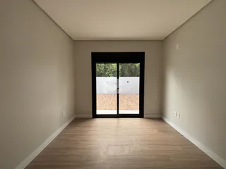 Vista de um corredor interno com piso de madeira clara.