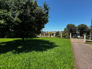 Uma vista externa do jardim verde com uma cerca no meio, sob um céu azul.