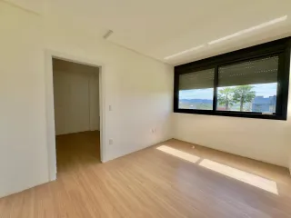 Sala de estar com piso de madeira clara e grande janela com vista para a paisagem.
