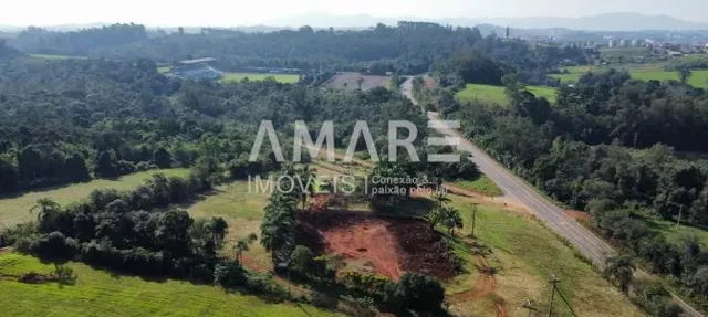 Vista aérea de uma área rural com vegetação e uma estrada de terra.