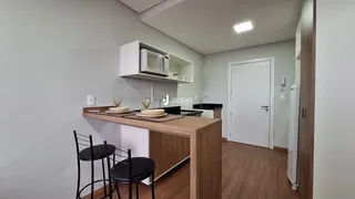 Vista interna de uma cozinha moderna com bancada de madeira e cadeiras.