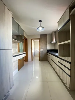 Cozinha moderna com armários brancos e piso claro.