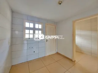 Foto interna de um cômodo com paredes brancas e uma janela.