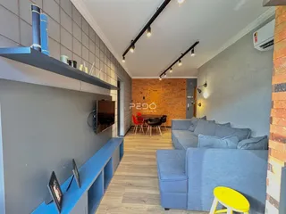 Ambiente de sala de estar e jantar com piso de madeira e parede de tijolos aparentes.