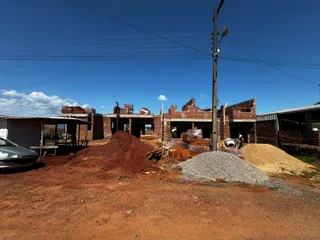 Foto de um canteiro de obras com estruturas de tijolos expostas e materiais de construção.