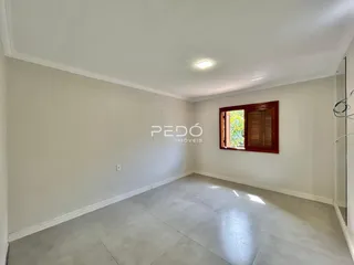 Sala de estar vazia com paredes brancas e piso claro.