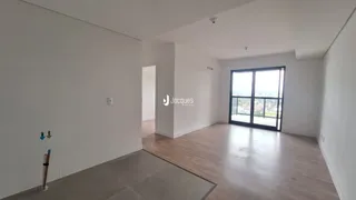 Ambiente interno de uma sala com piso de madeira e grande janela.