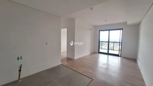 Ambiente interno de uma sala com piso de madeira e grande janela.