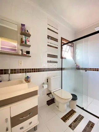 Foto de um banheiro com pia e box de vidro em uma residência.