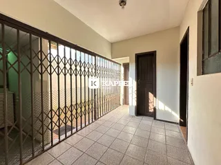 Corredor interno com piso de cerâmica e grade de proteção que dá acesso a uma área externa.