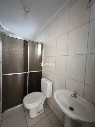 Foto de um banheiro com revestimento de azulejos brancos e louças sanitárias.