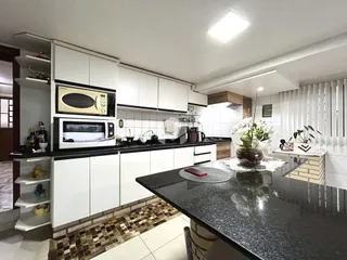 Esta é uma foto de uma cozinha moderna com armários brancos e bancadas escuras.