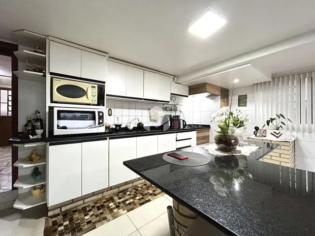 Esta é uma foto de uma cozinha moderna com armários brancos e bancadas escuras.