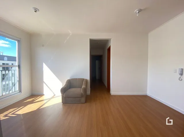 Vista interna de um corredor com piso de madeira clara e parede branca.