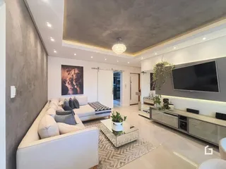 Sala de estar moderna com sofá e televisão em um apartamento.