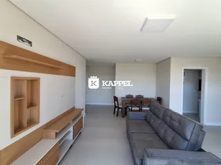 Sala de estar com sofá cinza e painel de madeira na residência.