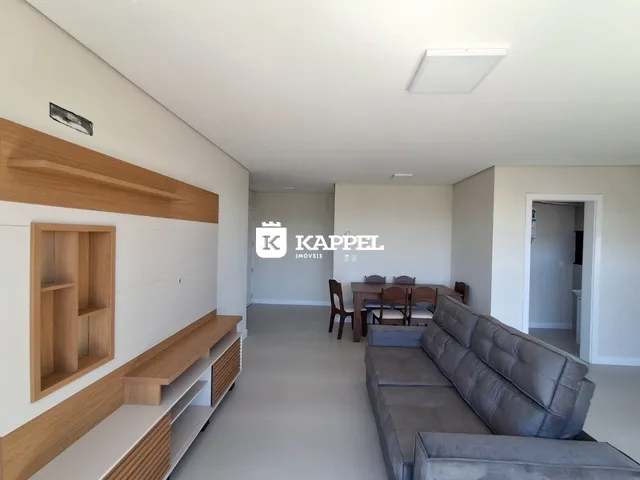 Sala de estar com sofá cinza e painel de madeira na residência.