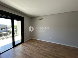 Sala de estar com piso de madeira clara e porta de vidro.