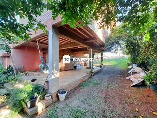 Foto da fachada de uma residência com área externa coberta e jardim.