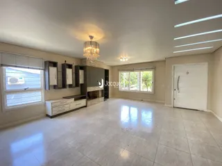 Sala de estar ampla com piso de cerâmica clara e iluminação moderna.