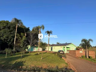 Vista externa da residência verde em Lajeado, com gramado e vegetação ao redor.