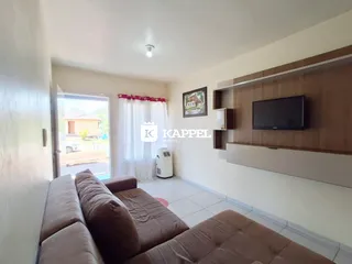 Sala de estar com sofá e porta de vidro que dá acesso ao exterior.