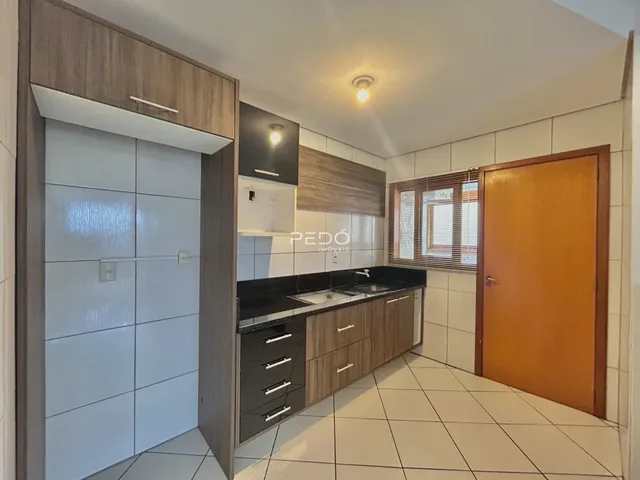 Cozinha moderna com armários e piso de cerâmica clara.