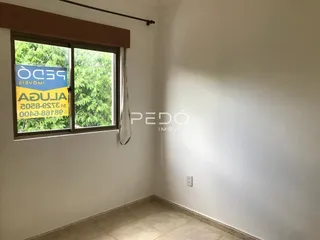 Vista interna de uma sala com janela e parede branca.