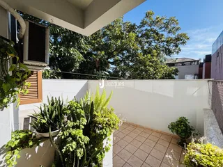Vista de uma área externa com plantas e piso de cerâmica em uma residência.