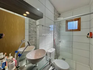 Banheiro moderno com azulejos brancos e bancada de vidro.